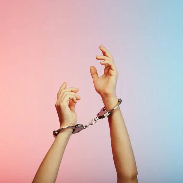 Handcuffed person raising hands in the air trying to reach