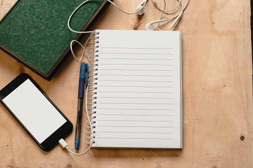 notepad, pen, book, headphone, mobile on wood desk. Inspiration concept