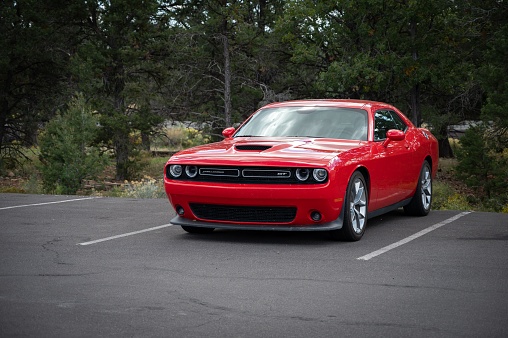 Fredonia, United States – October 04, 2022: A Nice red Dodge Challenger parked next to the forest in Fredonia, United States