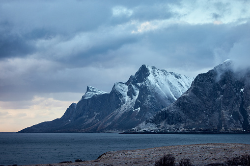 Snowcapped mountains with Norwegian sea in Lofoten.