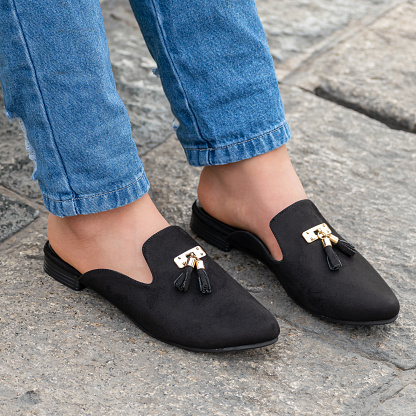 Closeup of a person wearing stylish and beautiful black colored mule shoes
