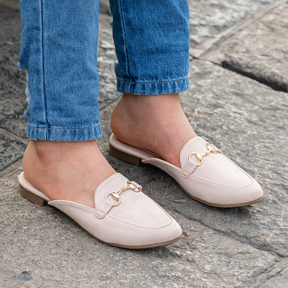 Closeup of a person wearing stylish and beautiful white colored mule shoes