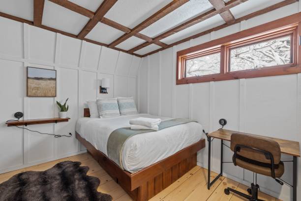 istock Comfortable white bedroom with a desk, chair, and extensive bed 1464693969