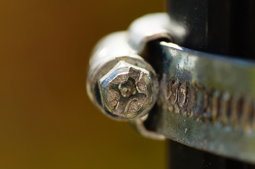 Macro image of the screw of a hose clamp. A Screw/band hose clamp.
