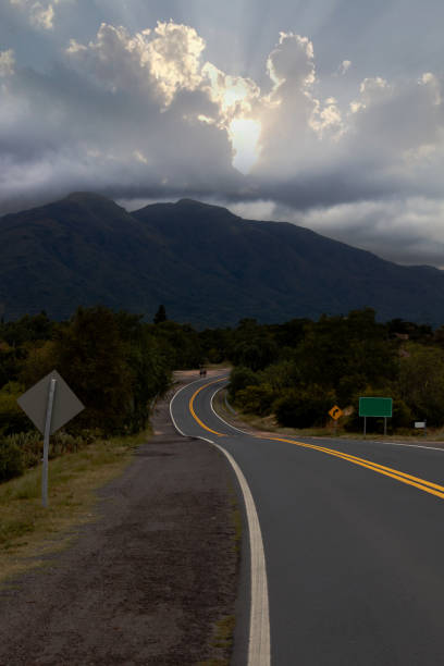 foto vertical de uma estrada vazia de pista única durante o pôr do sol sob um belo céu nublado - single lane road road sunset rural scene - fotografias e filmes do acervo