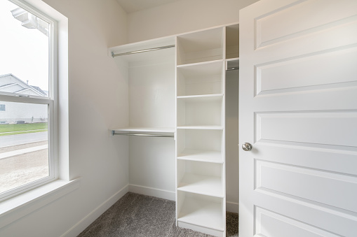 A minimalistic closet interior design in white color with a window