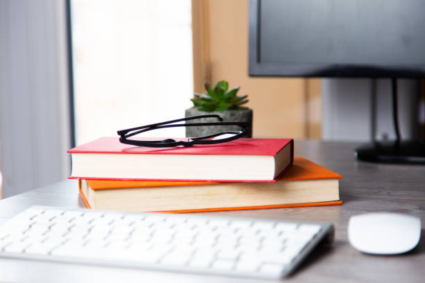 istock Computer desk with books, glasses, keyboard, and mouse on it 1464695776