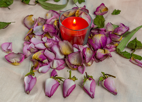 dried roses, candle and book on a cloth