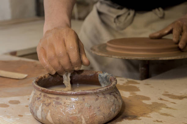 istock Craftsman working on a pottery wheel making a vase from clay 1464696780