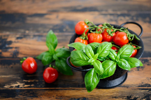 Fresh red cherry tomatoes with basil on a wooden background. Selective focus.