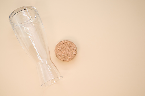 A closeup shot of a clear and clean empty glass with cork cover isolated on a pink background