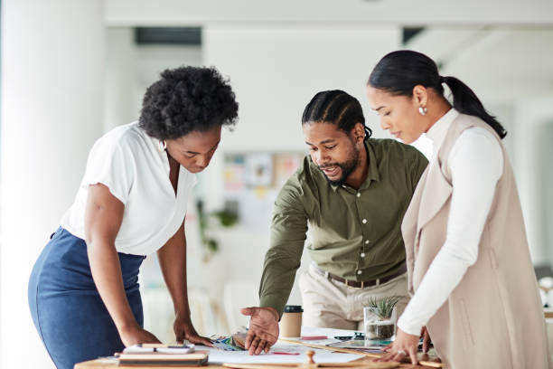 Collaboration, architecture and blueprint with a business team in an office working on a design for building. Architect, engineer and designer with a man and woman employee group at work on strategy