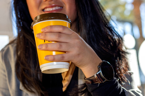 Close-up of a business girl with smartwatch drinking coffee.