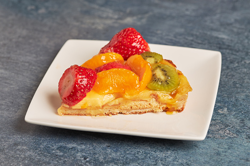 A portion of a delicious fruit and cream cake on a square white plate