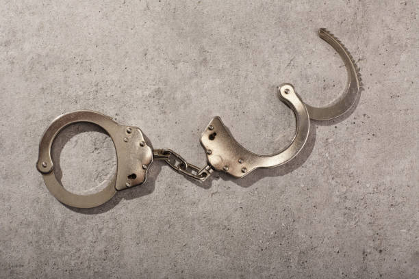 istock Handcuffs on concrete background with hard shadow 1464700354