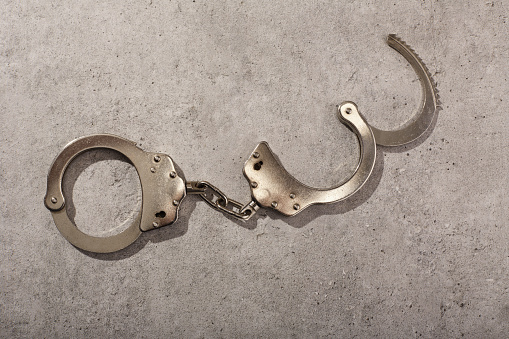 Handcuffs on concrete background with hard shadow