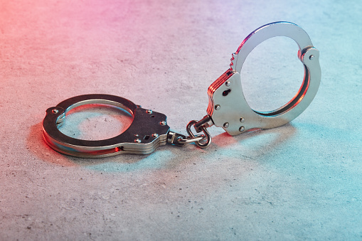 Handcuffs on concrete surface with police vehicle lighting