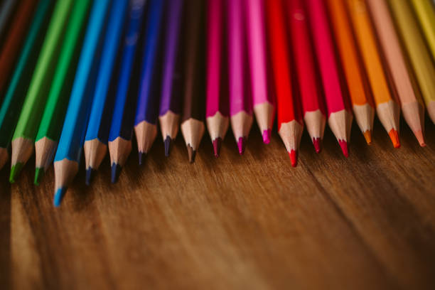 a bunch of colores pencils with similar colors scattered on a wooden table