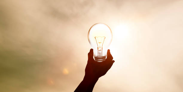 Light bulb in one hand from sunlight stock photo