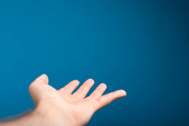 A man's open palm isolated on a blue background with space for text