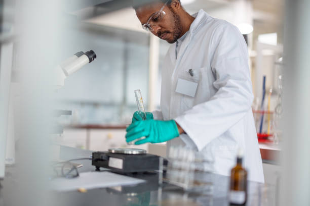 istock Dark-Skinned Scientist Holding A Test Tube While Putting A Beaker On A Scale 1464702677