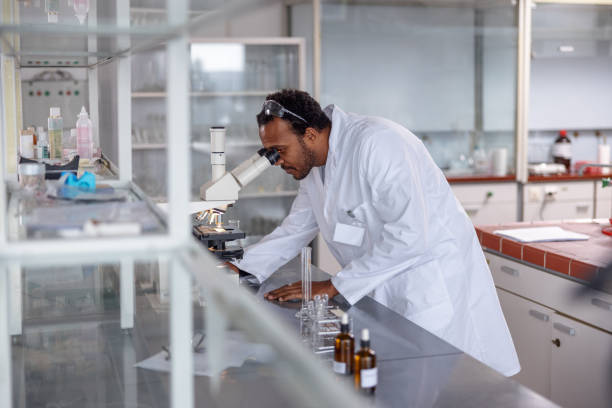 istock Side View Of An African Male Scientist Analyzing A Sample Through A Microscope At A Lab 1464703291