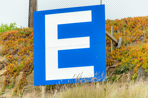 A closeup shot of a blue and white letter  signage on an autumnal field