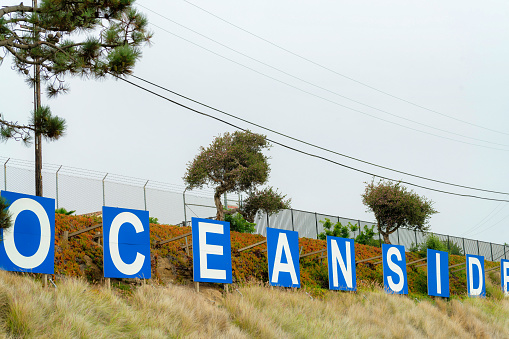 A scenic view of oceanside signage on a hill under a cloudy sky