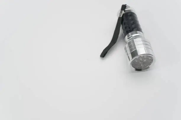 A closeup shot of a small black-silver flashlight isolated on a white background