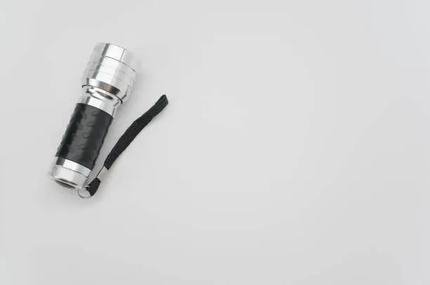 A top view of a small black-silver flashlight isolated on a white background