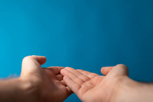 Closeup of a male shows outstretched hands isolated on a blue background A closeup of a male shows outstretched hands isolated on a blue background male is standing and shows outstretched hand with open palm stock pictures, royalty-free photos & images