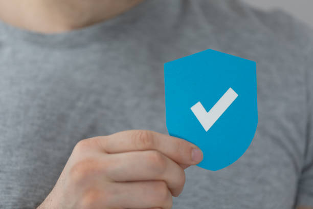 A male's hand holding a blue paper shield as a sign of security