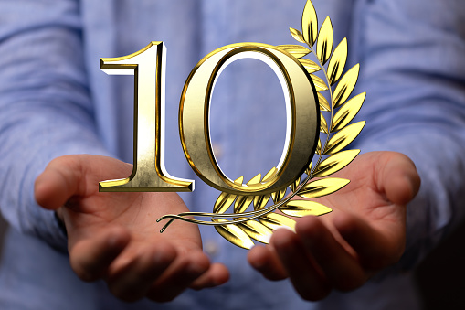 A 3d golden rendering of 10 with laurel wreath hovering over man's palms - anniversary and success concept