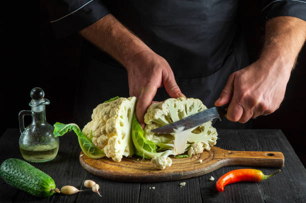 cook está cortando couve-flor em uma cozinha de restaurante. a ideia de uma deliciosa dieta para o café da manhã ou jantar - hotel commercial kitchen organic salad - fotografias e filmes do acervo