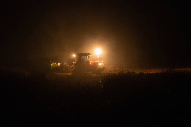 istock Street lamp and a tractor in a field during nighttime 1464707412