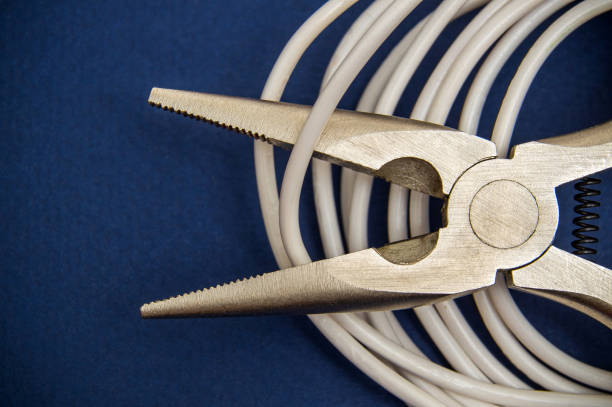 Wire cutters or diagonal pliers and white wires close up on dark blue background