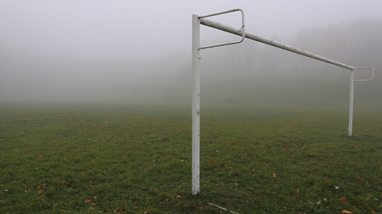 The gate without a net in a football field on a foggy day