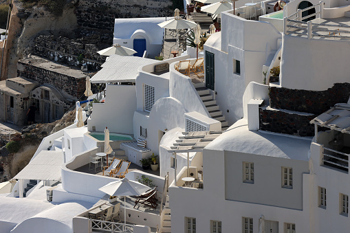 Oia, Santorini, Greece - June 28, 2021: Whitewashed houses with terraces and pools and a beautiful view in Oia on Santorini island, Greece