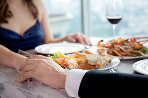 Hands of young couple date with romance together in anniversary at restaurant luxury for celebrate, man proposal woman for marriage while dining in atmosphere romantic, two people, valentine concept.