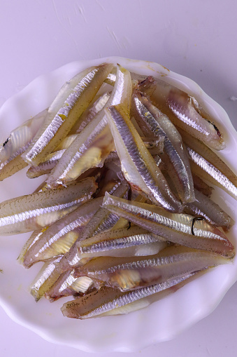 A top view of a plate of raw anchovies cleaned for cooking