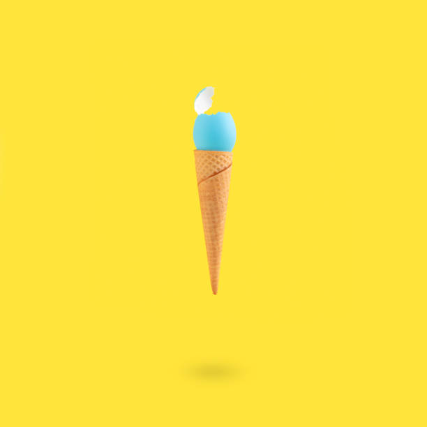 Vertical shot of a cracked blue egg on an ice cream cone on a yellow background