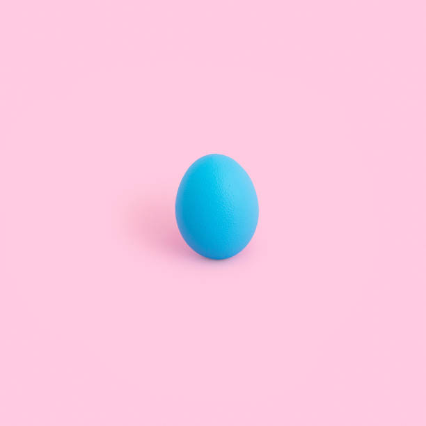 istock Vertical shot of a blue-painted egg on a pink background 1464711775