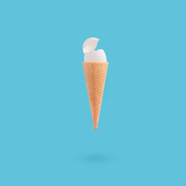 istock Vertical shot of a cracked white egg on an ice cream cone on a blue background 1464711784