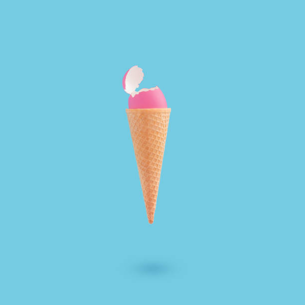 istock Vertical shot of a cracked pink egg on an ice cream cone on a blue background 1464711785