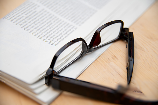 A closeup shot of a pair of reading glasses and a folded newspaper