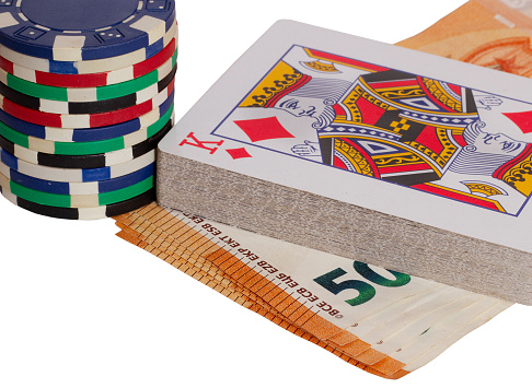 A closeup shot of 50 euro banknotes with poker chips and playing cards on white background