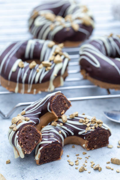 Closeup shot of a halved appetizing chocolate-covered raw donuts with nuts sprinkles