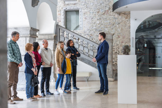 Attractive Adult Caucasian Male Museum Tour Guide Talking To His Diverse Audience stock photo