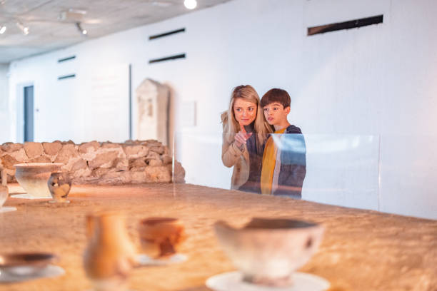 une mère blonde de race blanche éduque son jeune fils caucasien sur l’histoire tout en visitant un musée ensemble - child serious museum indoors photos et images de collection