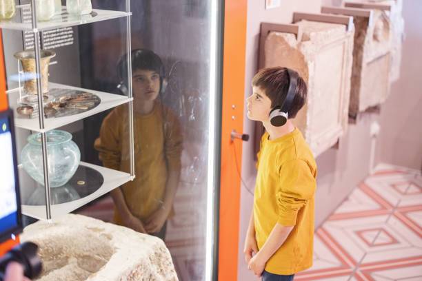 young caucasian boy with headphones listening to an audio tour guide while visiting the museum - ancient civilization audio imagens e fotografias de stock